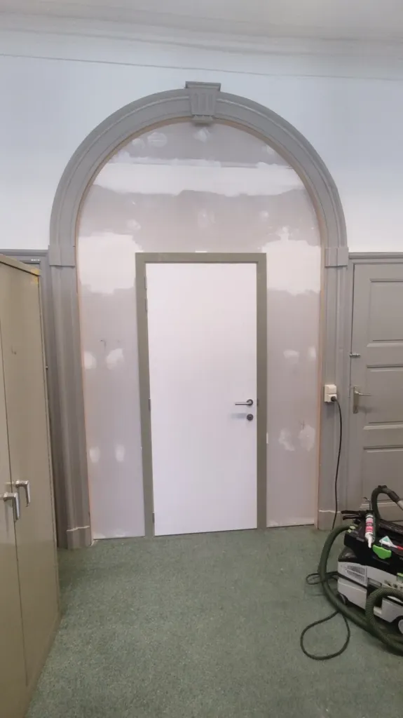 Nieuwe deur en wand ingebouwd in een historische boog, tijdens de werken