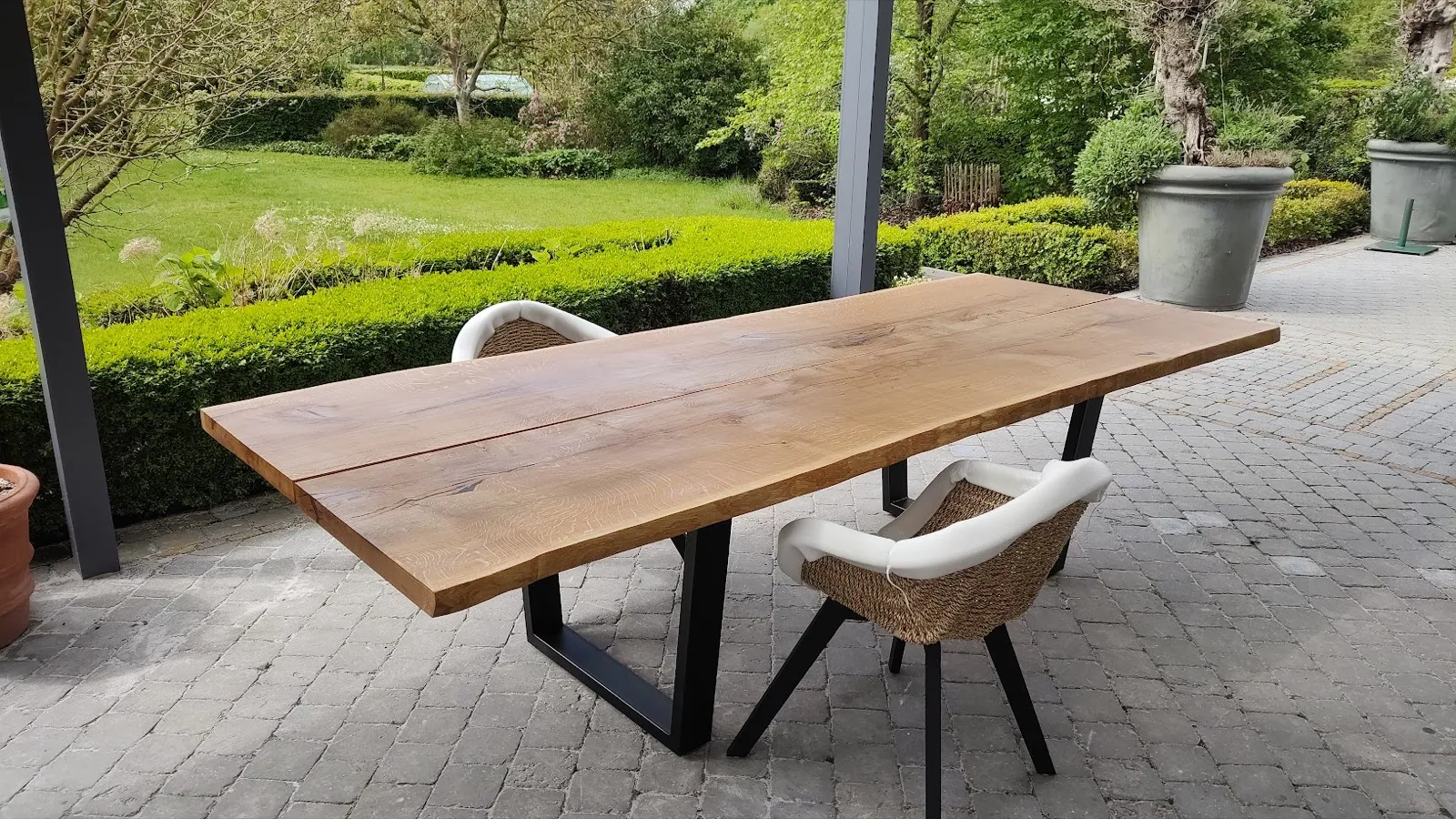Massief houten tafel met boomrand op een terras