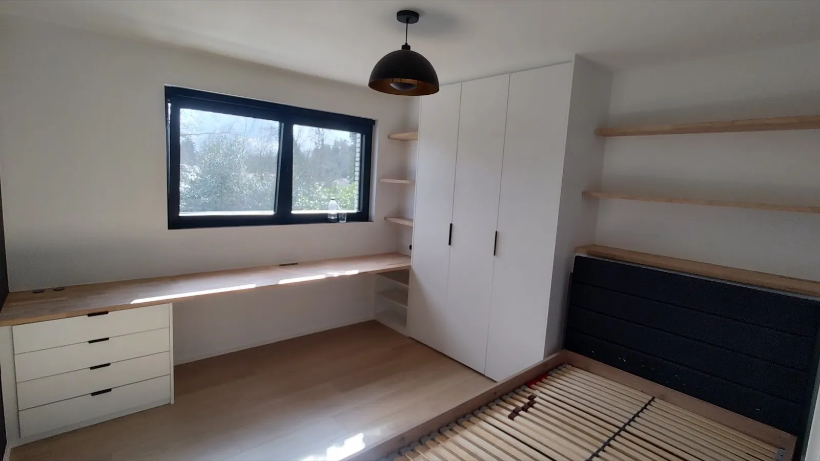 Kamer met kastwand, open legplanken en een lang bureau onder het raam, allemaal op maat